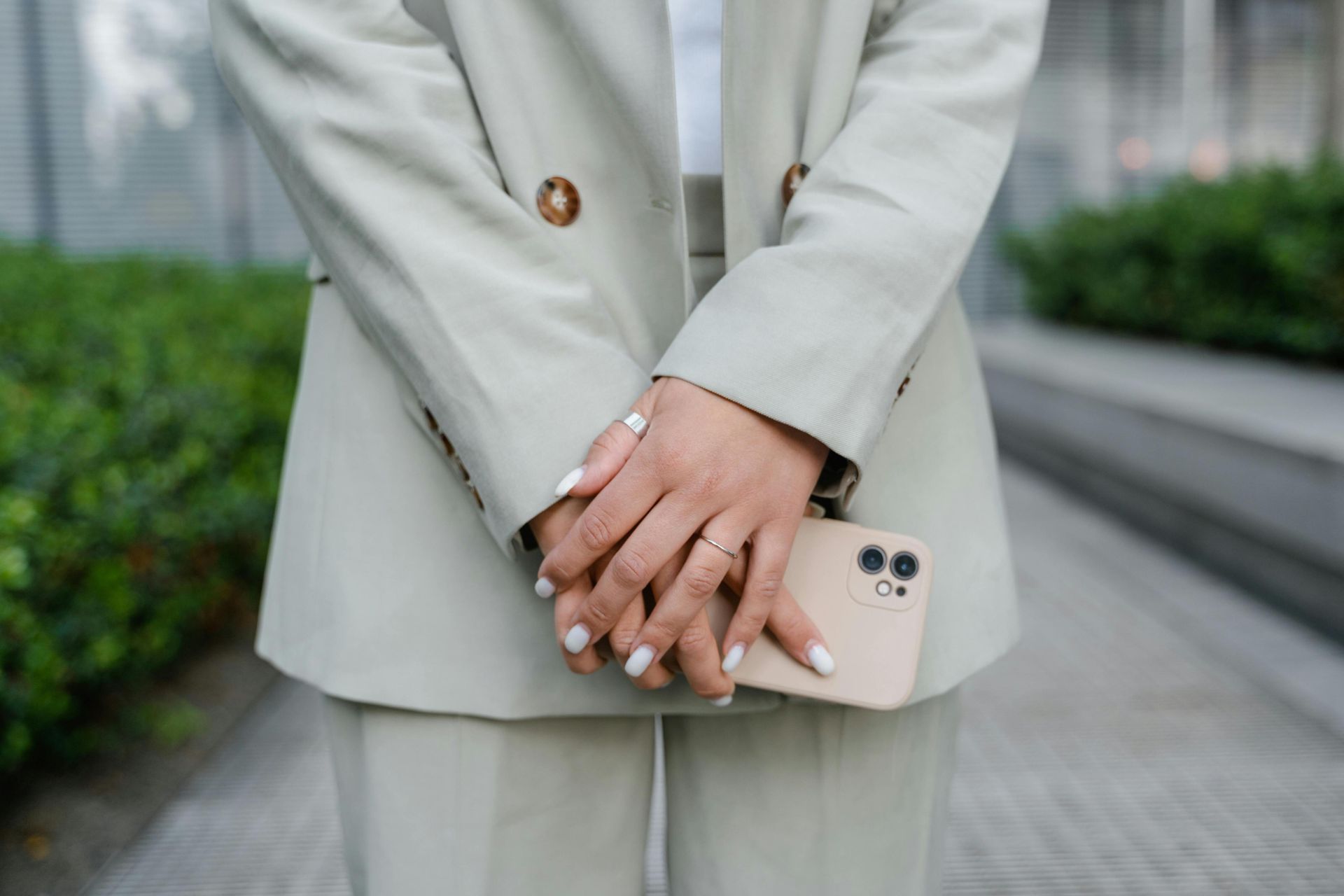 Close-up of a businesswoman's hands holding a smartphone, showcasing rings and manicure.