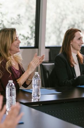 Focused business professionals clap during a conference meeting, capturing positive engagement.