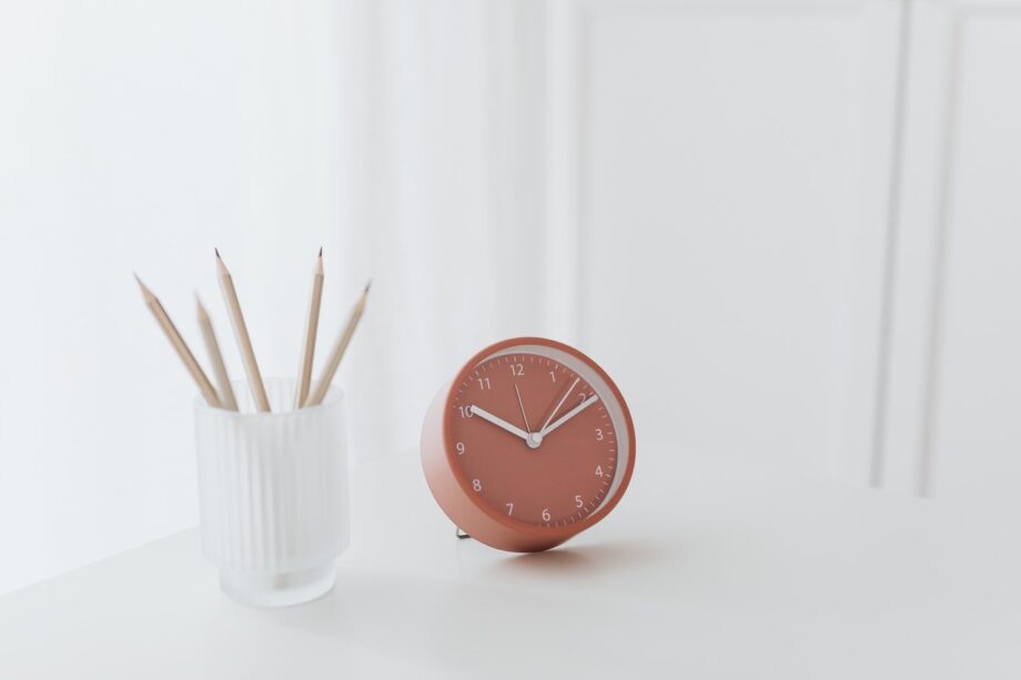 A clock sitting on top of a table next to pencils.